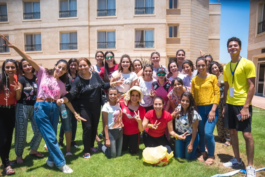 A group celebrating together on the grass, hands up and laughing