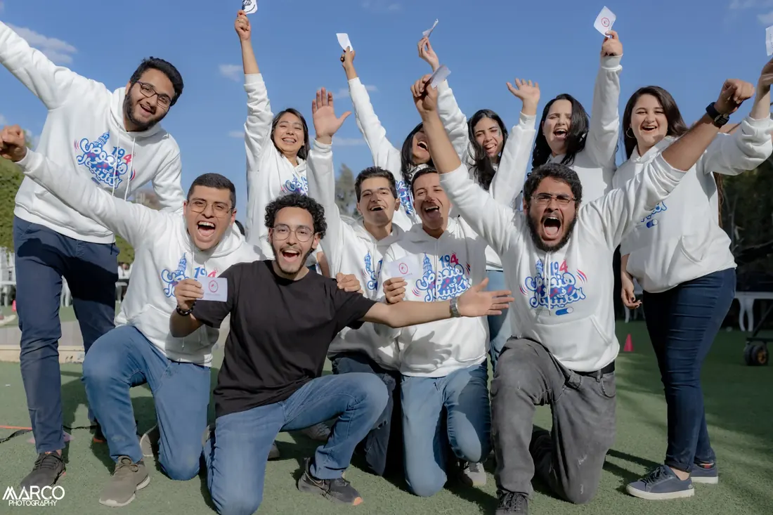 A group in white hoodies cheering with both arms raised
