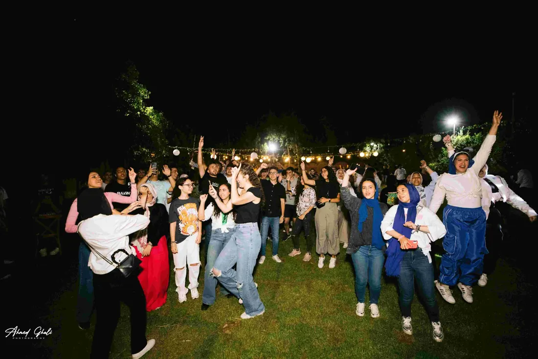 An evening crowd dancing under strings of lanterns