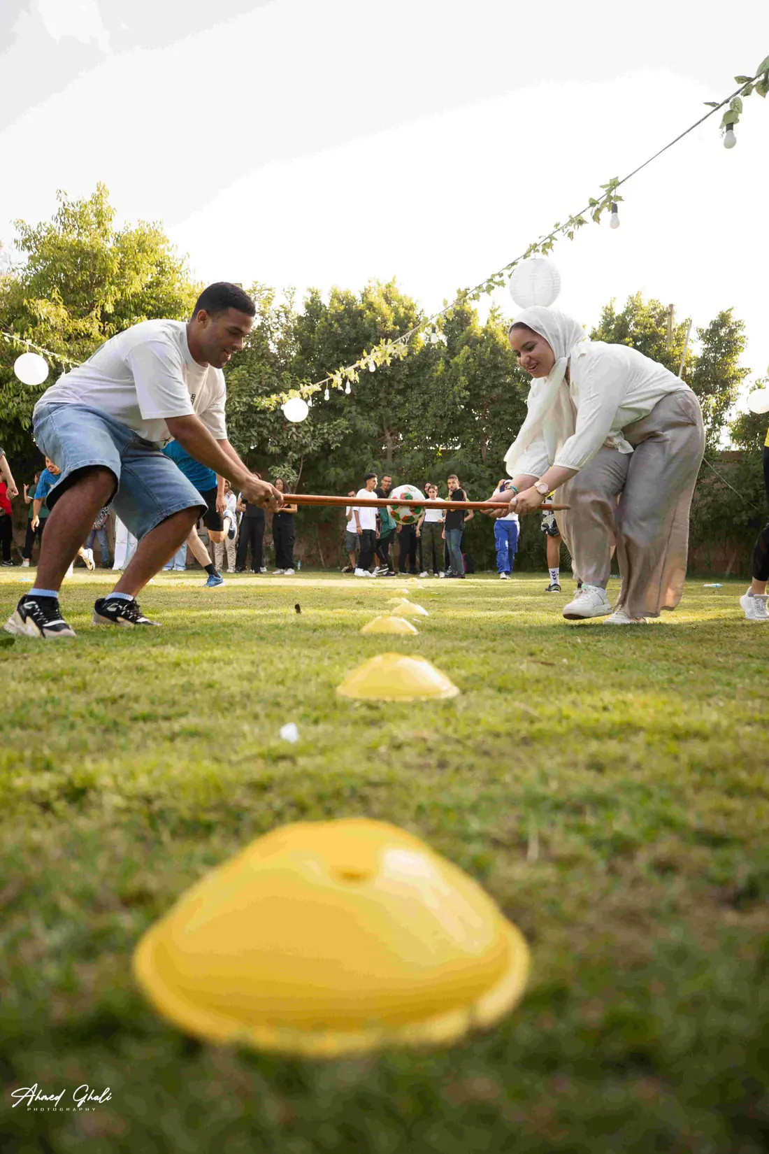 Two players leaning back against each other on a wooden stick during a balance game