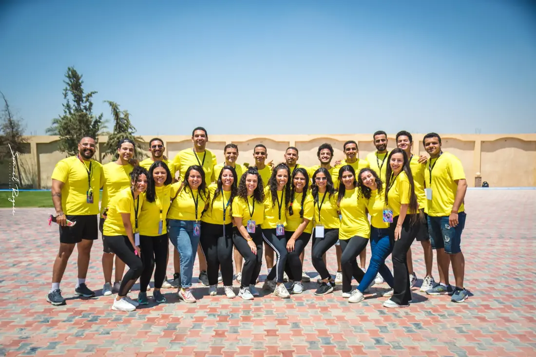 The AST crew in their yellow shirts, lined up on a sunny courtyard