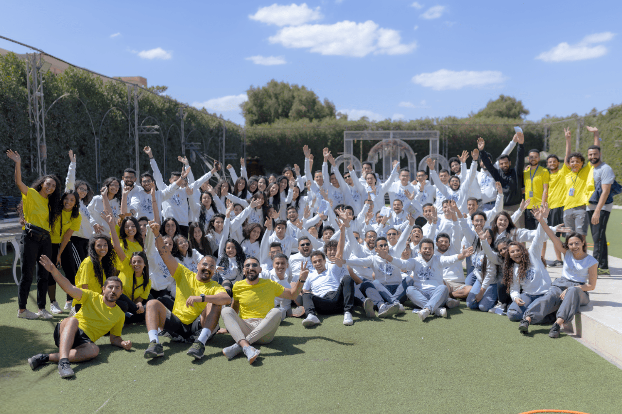 The AST team gathered on a pitch with hands in the air